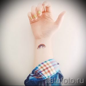 Фото простой татуировки с изображением радуги на запястье. Минималистичный дизайн и яркие цвета.