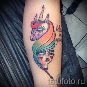 Фото татуировки на предплечье с изображением девушки и единорога, объединенных радужной гривой. Яркие цвета и сказочный дизайн.