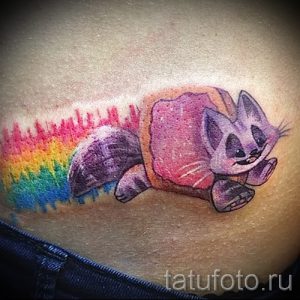 Фото тату милого кота с радужным хвостом. Яркие цвета, мультяшный стиль, оригинальный и забавный дизайн.