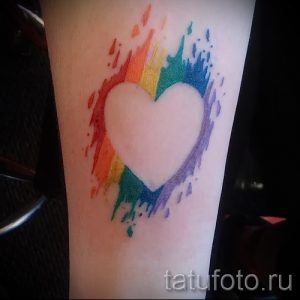 Фото тату акварельного сердца, окруженного радужными брызгами. Нежный, романтичный стиль, яркие цвета. Идеально для запястья или лодыжки.