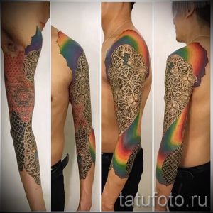 Большая татуировка на всю руку, сочетающая в себе радугу, геометрический узор и элементы мандалы. Сложный и детализированный рисунок татуировки.