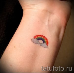 Небольшое тату радуги с белыми облаками на запястье. Простой и милый рисунок татуировки.