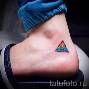Небольшое цветное тату треугольника с глазками на лодыжке. Яркий рисунок татуировки в стиле минимализм.