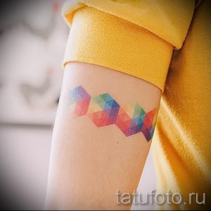Фото тату радуги в геометрическом стиле на предплечье. Татуировка, состоящая из разноцветных геометрических фигур, образующих радугу.