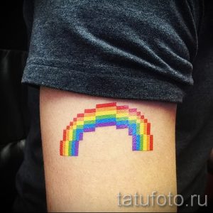 Фото тату с изображением радуги, выполненной в пиксельном стиле, на руке человека. Оригинальный и необычный рисунок татуировки.
