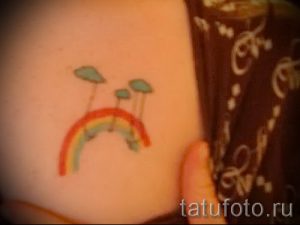 Фото тату радуги и облаков на коже. Нежный и минималистичный дизайн, яркие цвета, подходит для девушек.