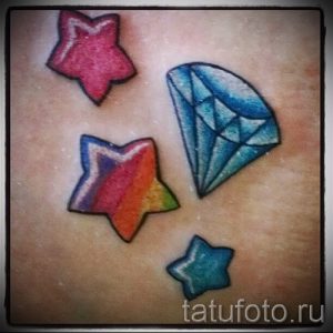 Фото тату с изображением звезд и бриллианта, выполненных в ярких цветах. Красочный и блестящий дизайн на коже.