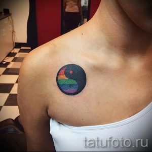 Фото тату Инь и Ян с радужной цветовой гаммой, расположенной на плече девушки. Символ гармонии и баланса в ярком исполнении.