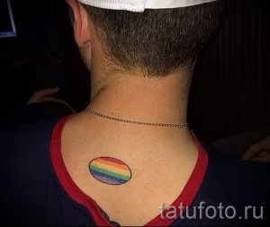 Фото тату: небольшая, минималистичная татуировка в виде радуги, расположенная на задней части шеи. Простой и стильный рисунок татуировки.