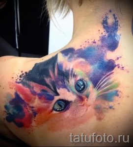 Фотография акварельной татуировки с изображением кошачьей морды, выполненной в пастельных тонах на шее девушки.