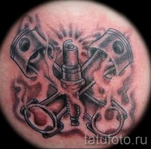 Фотография татуировки на голове, изображающей детали двигателя внутреннего сгорания: поршни, свечу зажигания и пламя. Реалистичный рисунок в черно-серых тонах.