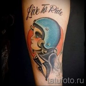 Фото тату: яркая олдскульная татуировка на руке с изображением девушки в мотоциклетном шлеме и надписью 'Live to Ride'.