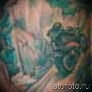 Фото тату с абстрактным рисунком, напоминающим кибернетические импланты и органические формы. Рисунок выполнен в зеленых и синих тонах.