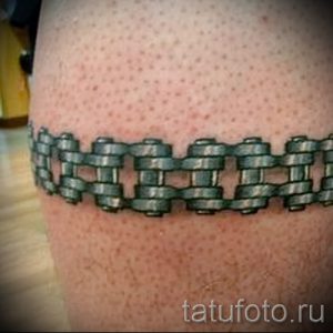 Фото тату цепи мотоцикла на лодыжке. Реалистичный рисунок, создающий иллюзию обхватывающей ноги цепи. Детализированная проработка звеньев.