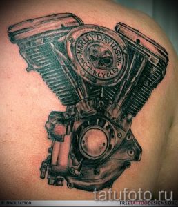 Фото тату двигателя Harley Davidson на плече. Детализированный рисунок в черно-серых тонах, реалистичная проработка деталей мотоцикла.