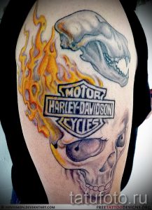 Фото тату на плече: череп в огне с логотипом Harley-Davidson. Детализированный рисунок татуировки в стиле байкерской тематики.