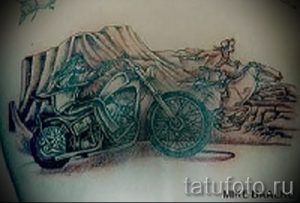 Фото тату: черно-белый рисунок мотоцикла на фоне горного пейзажа, выполненный в графическом стиле, с использованием штриховки и теней.