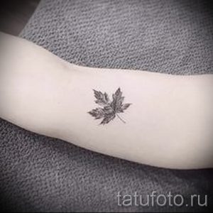 Фото маленькой татуировки с изображением кленового листа на руке. Черно-белый рисунок татуировки, выполненный в реалистичном стиле, выглядит изящно и стильно.