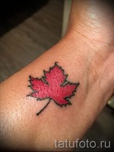 Фото маленькой татуировки с изображением красного кленового листа на запястье. Простой и элегантный рисунок татуировки, идеально подходящий для первого тату.