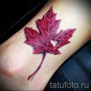 Фото татуировки кленового листа с вырезанным сердцем внутри. Красивая и детализированная татуировка на руке, выполненная в реалистичном стиле с использованием красных оттенков.