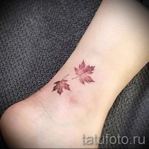 Фото тату двух маленьких красных кленовых листьев на женской лодыжке. Простой и элегантный рисунок татуировки, выполненный в минималистичном стиле.