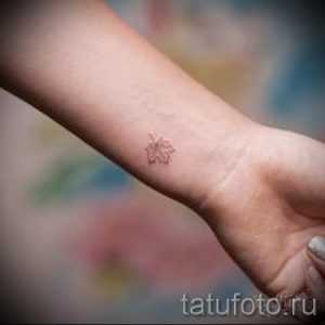 Фото тату маленького красного яблока на женском запястье. Простой и элегантный рисунок татуировки, выполненный в минималистичном стиле.