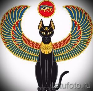Фото тату с изображением черной кошки Бастет с распростертыми крыльями и глазом Гора над головой. Яркие цвета и детализированная прорисовка.
