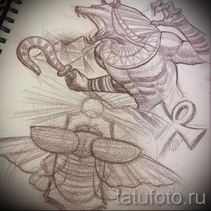 Эскиз татуировки, изображающий египетского бога с головой шакала, держащего в руке анкх, и скарабея внизу, выполненный карандашом.