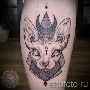 Фото тату кошки Бастет в стилизованном дизайне с головным убором и символом Анкх на груди. Изображение выполнено в технике дотворк.