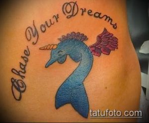 Фото тату головы единорога в синих тонах с крыльями и надписью "Chase Your Dreams". Мотивационный дизайн.