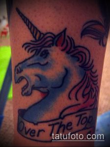 Фото тату головы единорога в синих тонах с надписью "Over The Top". Оригинальный дизайн и яркий стиль.