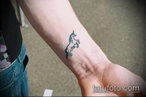 Фото минималистичной татуировки единорога в виде контура на запястье. Простой и элегантный рисунок.