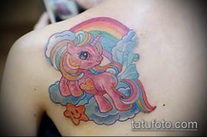 Фото тату единорога My Little Pony на плече. Яркая радуга, облака и звезда дополняют милый рисунок татуировки.
