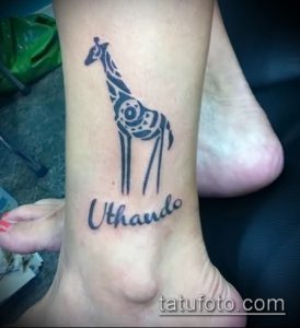 Фото тату жирафа на лодыжке с надписью 'Uthando'. Стильный рисунок татуировки с африканскими мотивами.