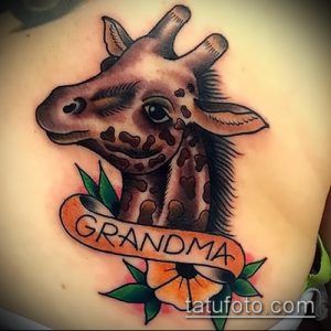 Фото тату: олдскульная татуировка жирафа с яркой надписью "Grandma" и цветком. Классический стиль с четкими контурами.