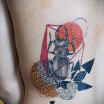 Фото татуировки жука-носорога на боку, выполненной в геометрическом стиле с использованием ярких цветов.