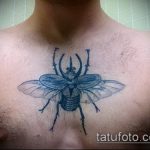 Фото тату жука-носорога на груди. Черно-белый рисунок с минималистичным дизайном.