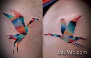 Фотография цветной татуировки на плече с изображением бумажного журавлика, состоящего из разноцветных геометрических фигур.