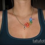 Фото тату золотой рыбки на ключице, выполненное в ярких, радужных цветах. Небольшой рисунок татуировки с детальной прорисовкой плавников и чешуи.