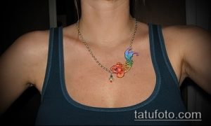 Фото тату золотой рыбки на ключице, выполненное в ярких, радужных цветах. Небольшой рисунок татуировки с детальной прорисовкой плавников и чешуи.