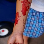 Фото простой татуировки с двумя красными рыбками на руке ребенка. Минималистичный рисунок, яркий цвет, подходит для временного нанесения.