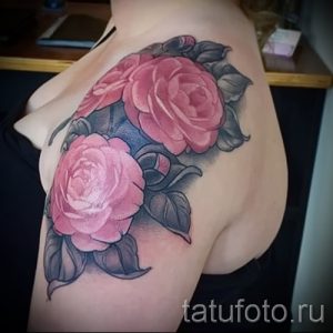 Фото тату двух розовых камелий с серыми листьями на плече. Реалистичный рисунок с плавными переходами цветов и детальной проработкой лепестков.