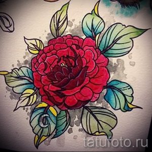 Фото тату красной камелии с зелеными и желтыми листьями. Динамичный рисунок с брызгами краски, выполненный в стиле олд скул.