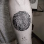 Фото минималистичной татуировки на предплечье, изображающей лицо, выполненное из множества тонких параллельных линий.