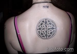 Фото татуировки кельтского узла на спине девушки. Черно-белый рисунок татуировки с изящными линиями и сложным дизайном.