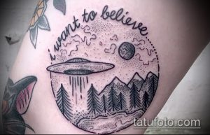 Фото тату: черно-белая татуировка в стиле dotwork с изображением НЛО над горами и лесом. Надпись 'I want to believe'.