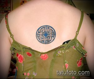 Фото тату: Кельтский узел, выполненный в синих тонах, на спине девушки. Сложный орнамент с переплетающимися линиями.
