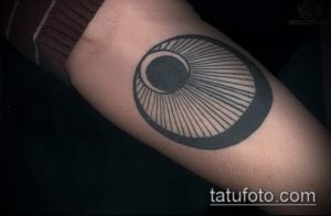 Фото тату: Геометрическая татуировка на предплечье, изображающая круг с радиальными линиями внутри. Черно-белый рисунок.