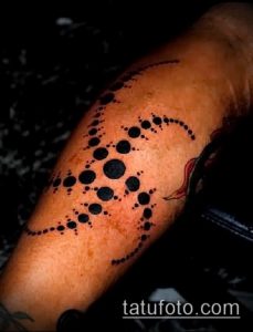 Фото тату в технике dotwork на плече. Черные точки, образующие абстрактный узор, напоминающий крыло или перо.