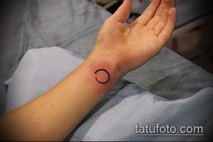 Фото тату открытого круга на запястье. Простой и стильный рисунок татуировки, выполненный черными чернилами. Подходит для тех, кто ценит лаконичность.